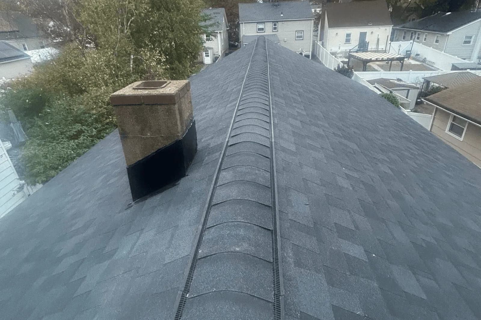 Completed Vesta asphalt shingle roof with ridge vent and chimney flashing